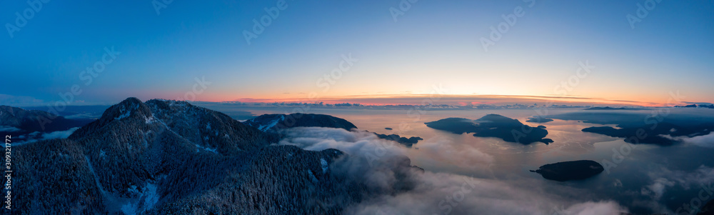 Obraz premium Aerial Panoramic View of Canadian Mountain Landscape on the Pacific Ocean Coast during a colorful sunset. Taken in Howe Sound near Vancouver, British Columbia, Canada.
