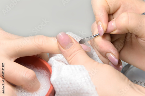 Nail Care Procedure. Nail salon  manicurist removes cuticles from a woman s fingernails