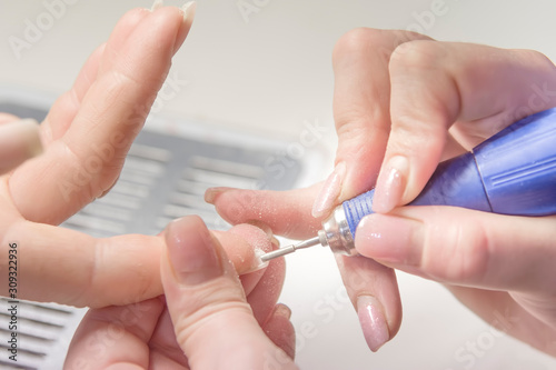Nail Care Procedure. Nail salon  manicurist polishes a woman s nails.