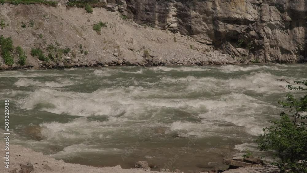 Powerful stream of mountain river flows in Crimea on summer day. Beautiful natural landscape of clear waters surrounded by gray cliffs with vegetation below. Wild nature in countryside. Concept