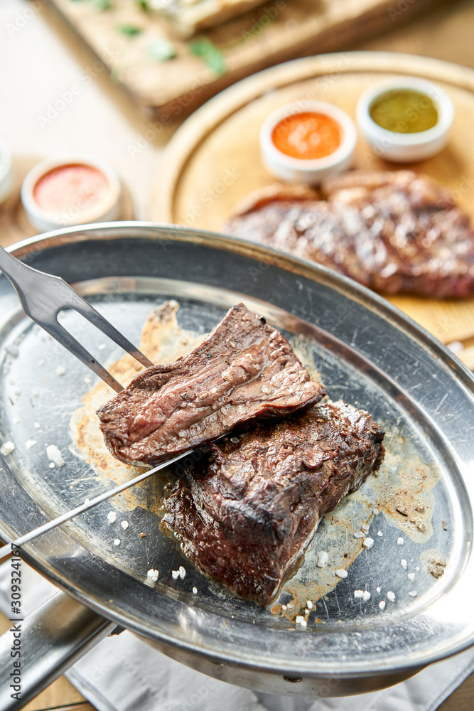 The waiter is butchering griled meat with a knife. Grilled fillet steaks with Pickled cabbage and two sauces.. Barbecue restaurant menu. The waiter is butchering griled meat with a knife. Grilled fillet steaks with Pickled cabbage and two sauces.. Barbecue restaurant menu.