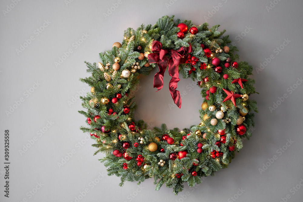 Beautiful festive wreath of fresh spruce on Gray wall. Xmas circlet with red and gold ornaments and balls. Christmas mood. Beautiful festive wreath of fresh spruce on Gray wall. Xmas circlet with red and gold ornaments and balls. Christmas mood.