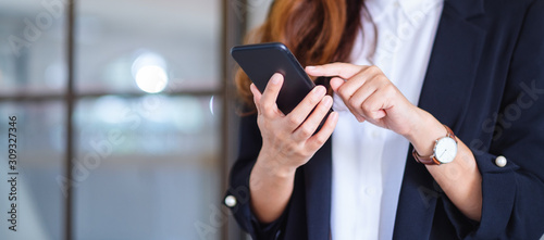 Closeup image of a businesswoman holding and using mobile phone photo