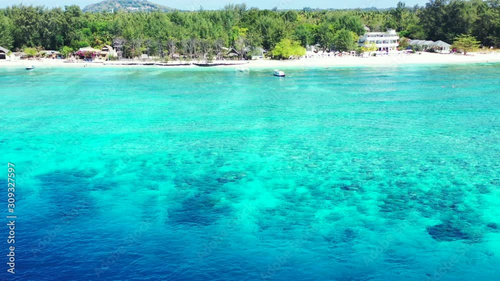 Peaceful tropical bay with white sandy beach washed by blue turquoise water of calm lagoon in front of tropical island with green lush vegetation Peaceful tropical bay with white sandy beach washed by blue turquoise water of calm lagoon in front of tropical island with green lush vegetation