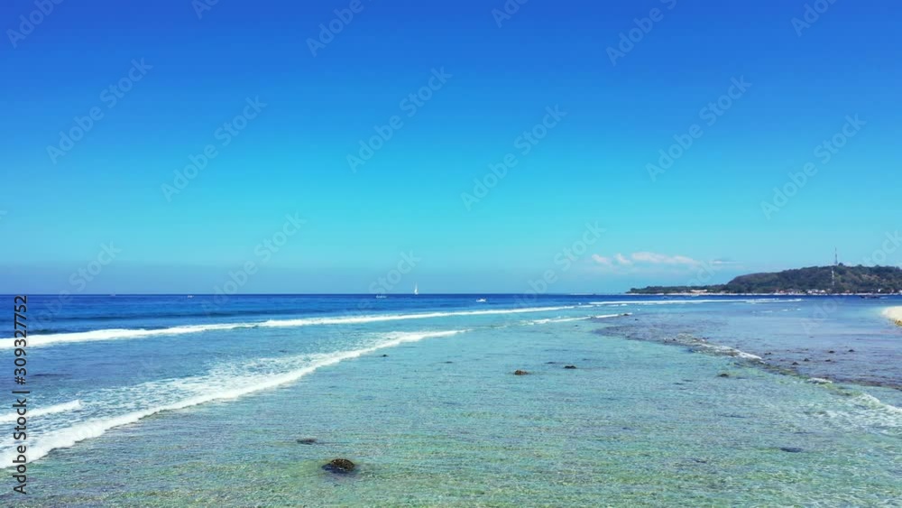 White waves washing rocky sea bottom on shore of tropical island, beautiful seascape with blue sea and sky on a bright morning in Indonesia White waves washing rocky sea bottom on shore of tropical island, beautiful seascape with blue sea and sky on a bright morning in Indonesia