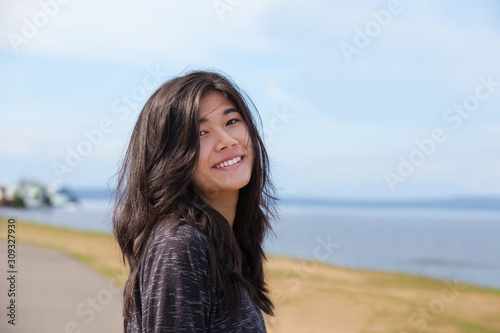 Smiling biracial Asian Caucasian teen girl with ocean background