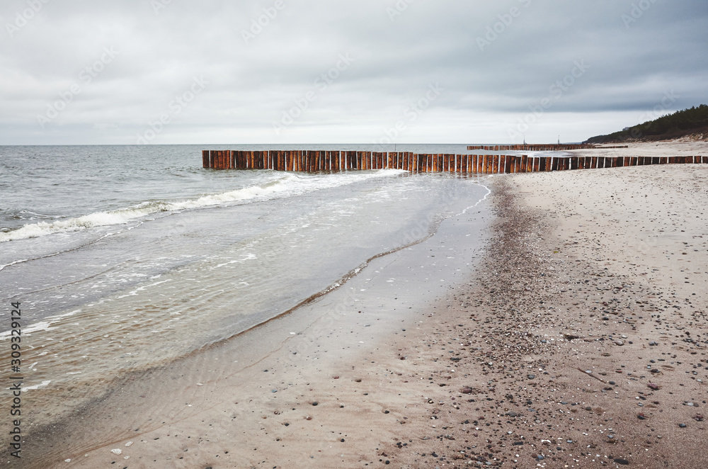 Empty beach on a cloudy day with wooden groin in distance.