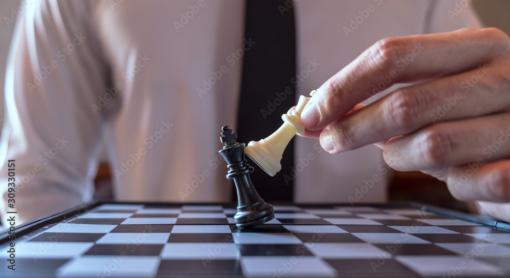 Closeup photo of businessman playing chess and beating black king Closeup photo of businessman playing chess and beating black king