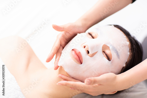 Young beauty with facial mask in spa salon