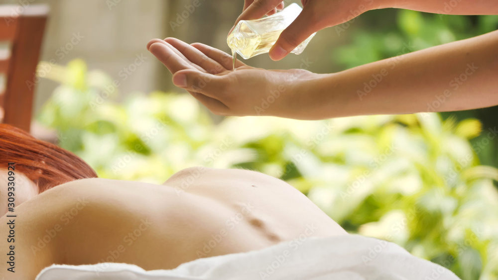 Massage therapist pouring essential oil for massage at spa. - obrazy, fototapety, plakaty 