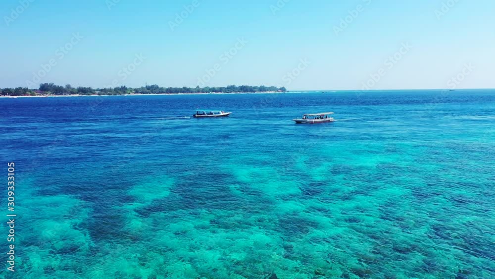 Bali, Indonesia, two fishing boats sailing on the crystal clear sea, small island in the background, aerial Bali, Indonesia, two fishing boats sailing on the crystal clear sea, small island in the background, aerial