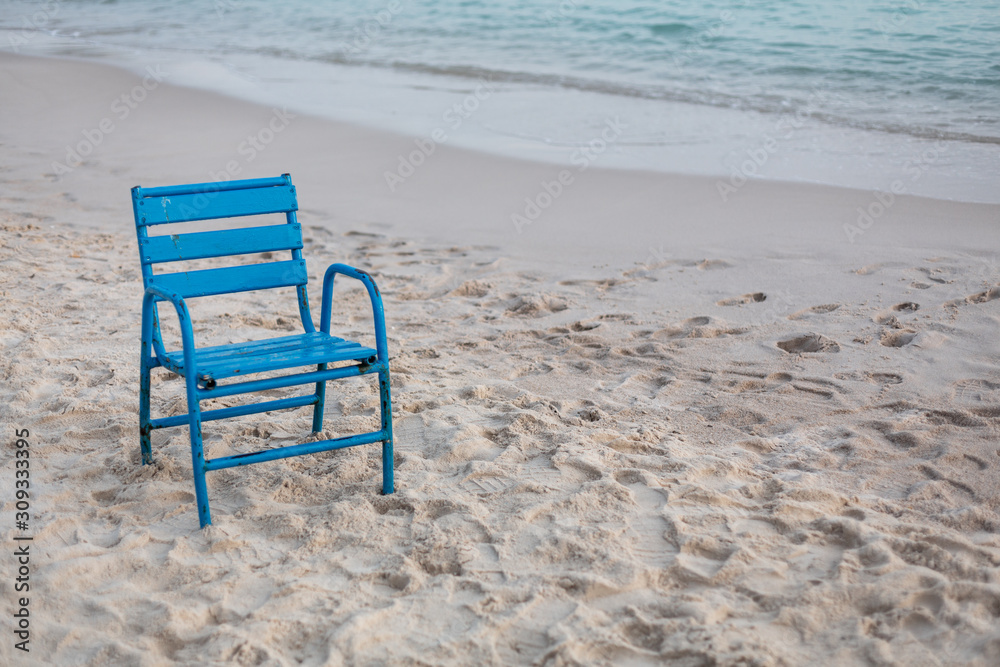 Blauer Stuhl steht einsam im Sand am Strand
