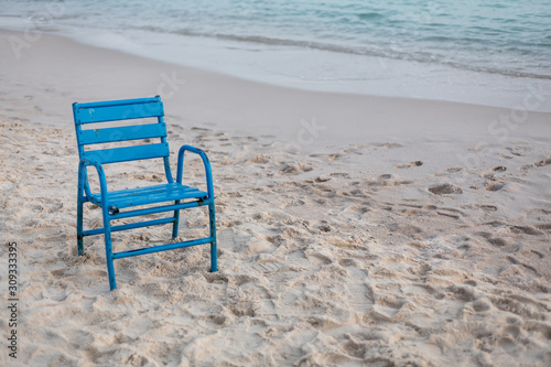 Blauer Stuhl steht einsam im Sand am Strand
