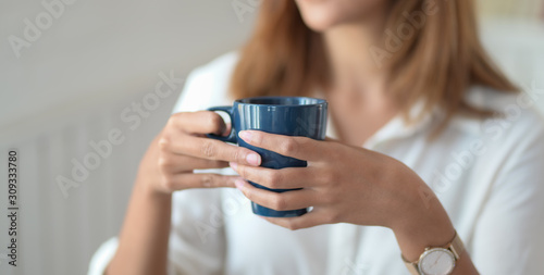 Close-up view of young beautiful businesswoman working on her project while drinking a coffee cup