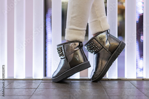 beautiful female silver uggs with rhinestones on the legs of the model in the interior. Side view. Shoe store. Festive shoes