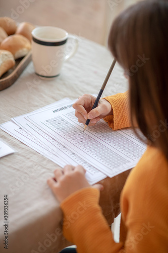 Long-haired girl in orange outfit doing her homework