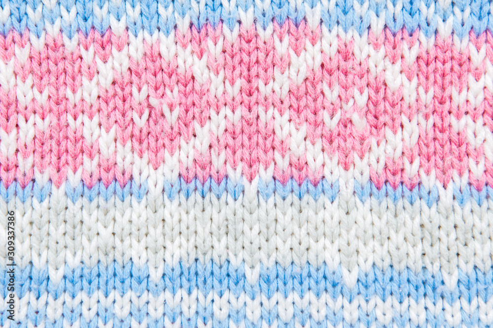Closeup of knit fabric background with knitted white, blue and pink geometric pattern