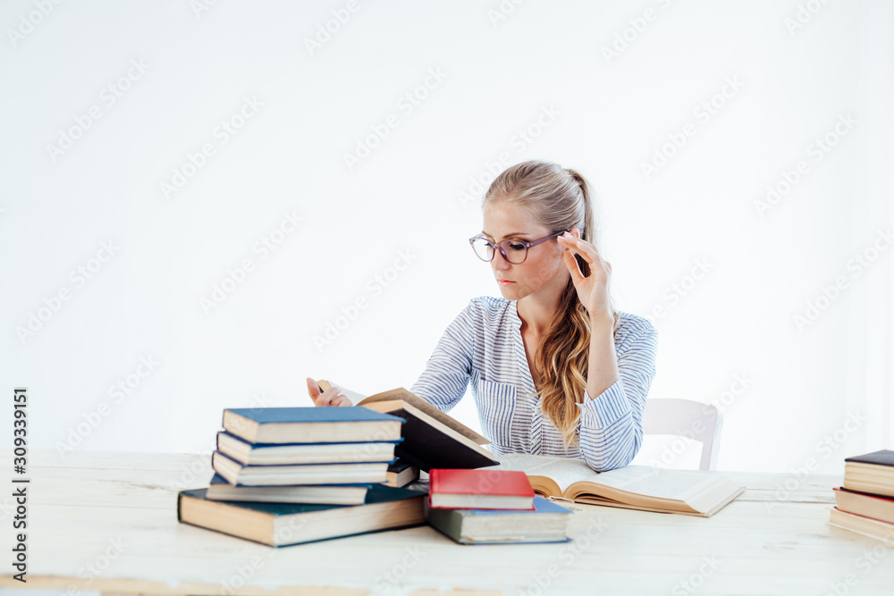 female teacher sitting at a table of many books Office female teacher sitting at a table of many books Office