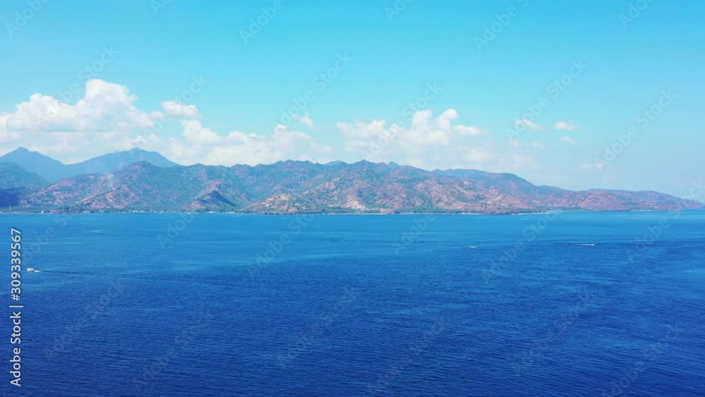The Peaceful Movement Of The Water Background WIth High Mountains And Bright Cloudy Sky During Summer, Indonesia Deep Blue Ocean - Wide Shot The Peaceful Movement Of The Water Background WIth High Mountains And Bright Cloudy Sky During Summer, Indonesia Deep Blue Ocean - Wide Shot