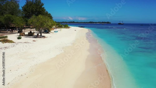 tropical island and luxury vacation background. soft white sand beach, exotic trees, crysal clear aquamarine sea water and boats photo