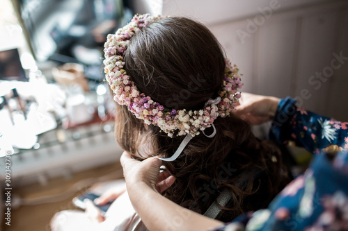 Junge Frau bekommt einen Blumenkranz ins Haar gesteckt