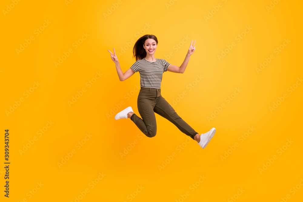 Full size photo of cheerful playful girl jump relax spring free time make v-signs wear good looking clothes isolated over shine color background