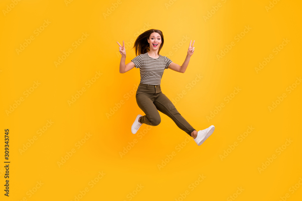 Full length photo of funky youth girl rest relax spring free time jump make v-sign wear stylish clothes isolated over bright color background