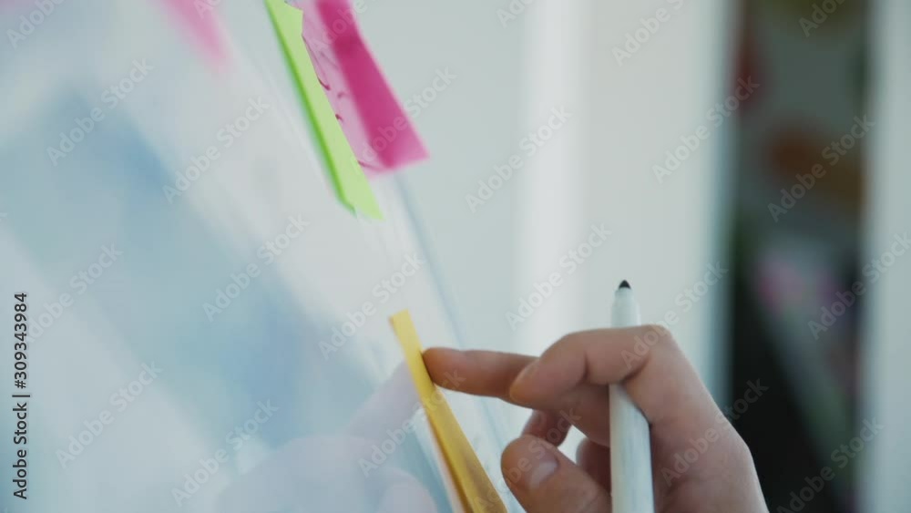 Concept of brainstorming new ideas. Clever, professional and confident graphic or web designer attach sticker on special board. Man spending day indoor coworking space with modern interior office