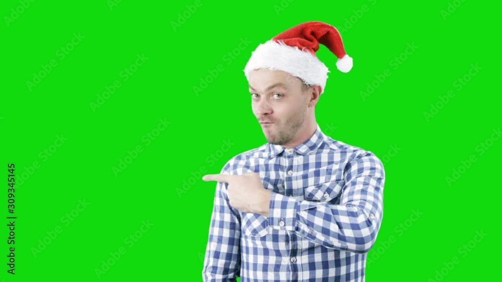 Funny guy in Santa hat indicating finger empty space advising new product on green background. Chroma key Funny guy in Santa hat indicating finger empty space advising new product on green background. Chroma key