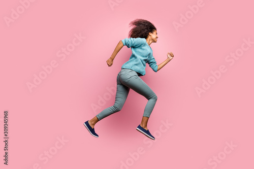 Profile side full length body size photo of cheerful casual cute youngster aspiring to come for sales on time jumping running in grey pants blue jumper shoes isolated pastel color background