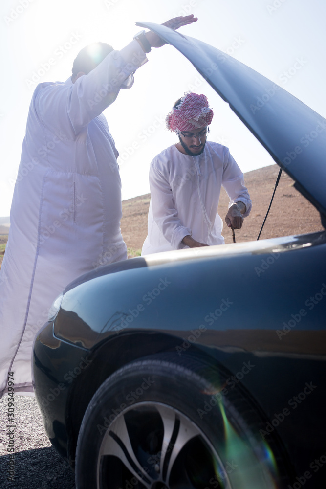Two young Arab men having car issue on the road