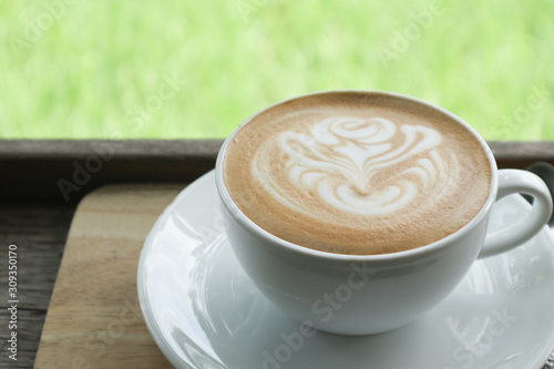 Coffee cup latte art in heart shape with a cup of dark coffee and dark chocolate on wooden table.Frothy drink for coffee break after working or weekend meeting