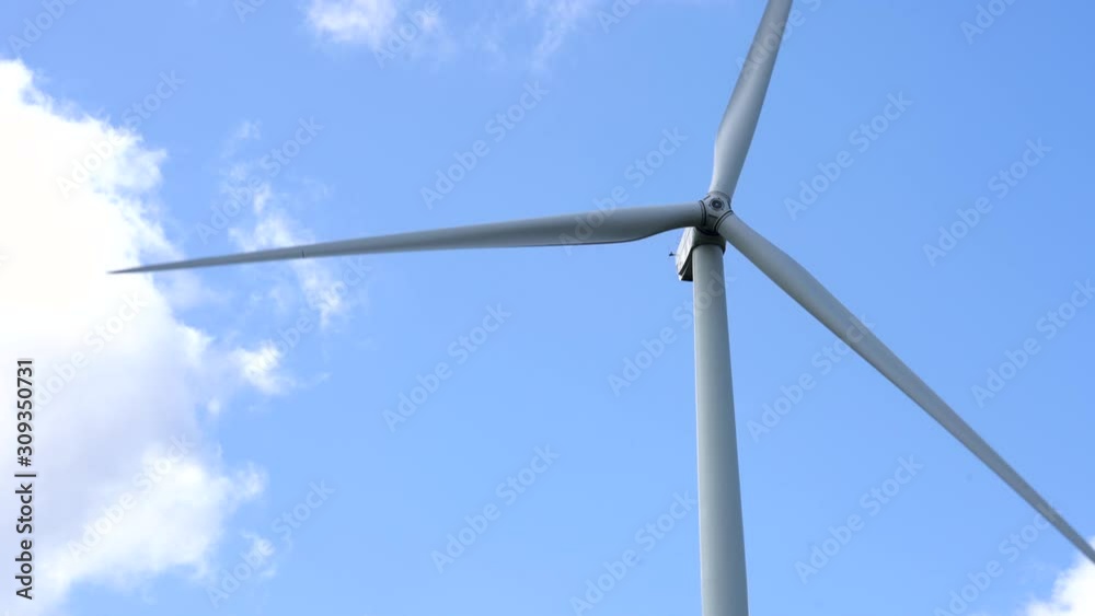 Long shot detail of wind turbine blades spinning in the wind with summer blue sky background Long shot detail of wind turbine blades spinning in the wind with summer blue sky background