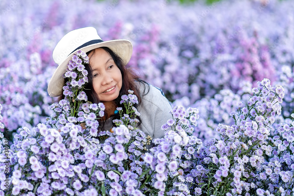 Portrait of teenage girl in a garden of flowers, Young happy asian girl in Margaret Aster flowers field in garden at Chiang Mai, Thailand