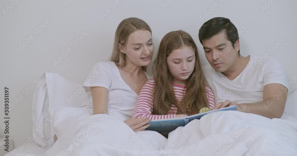 Family reading book together in bed. Caucasian man, woman and child. Reading and having fun. Family reading book together in bed. Caucasian man, woman and child. Reading and having fun.