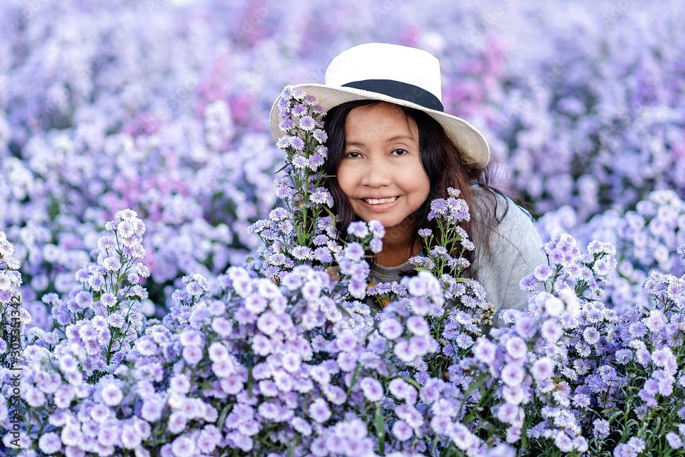 Portrait of teenage girl in a garden of flowers, Young happy asian girl in Margaret Aster flowers field in garden at Chiang Mai, Thailand