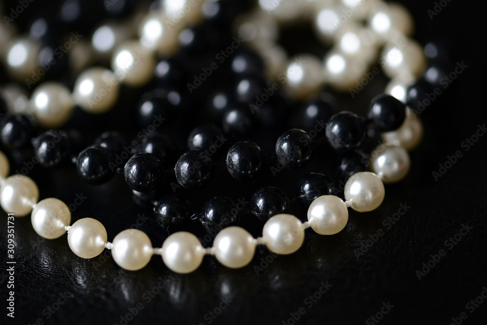 Fragment of a necklace of black and white beads on a black background close-up. Fashion background Fragment of a necklace of black and white beads on a black background close-up. Fashion background