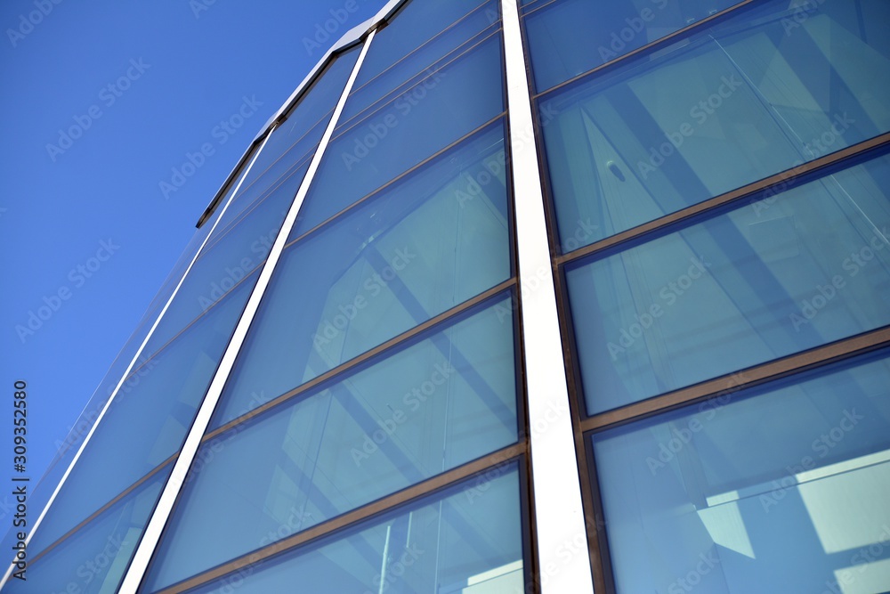 Modern office building wall made of steel and glass with blue sky Modern office building wall made of steel and glass with blue sky