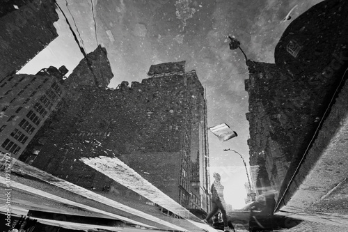Manhattan in puddle reflection with pedestrians, traffic lights, cloudy sky