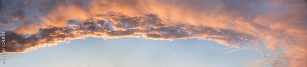 wide dreamy sunset panorama with lighted clouds and blue sky in the lower half - obrazy, fototapety, plakaty 