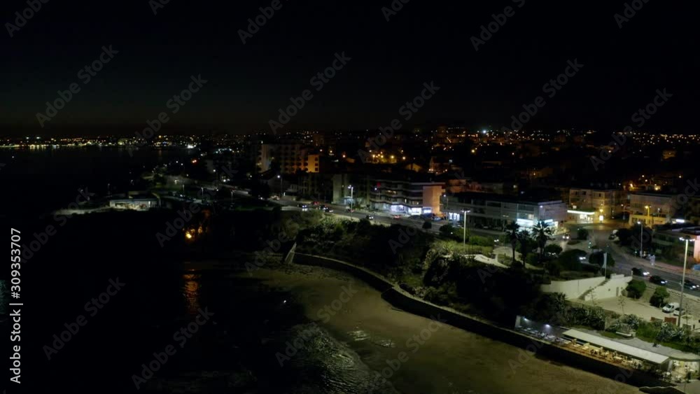 Aerial, pan, drone shot, overlooking the Sao pedro do Estoril cityscape, the Portuguese coast and the sea, at night time, in Lisbon, Portugal Aerial, pan, drone shot, overlooking the Sao pedro do Estoril cityscape, the Portuguese coast and the sea, at night time, in Lisbon, Portugal