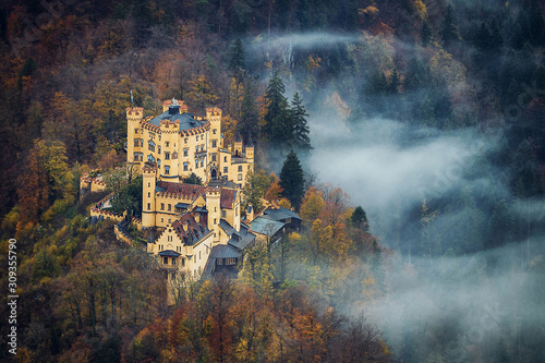 Aerial view of famous Hohenschwangau bavarian castle with a beautiful fog on the forest in autumn season photo