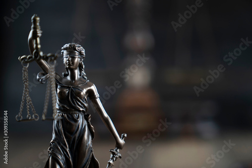 Justice concept. Themis statue  on the rustic wooden table and the dark background.