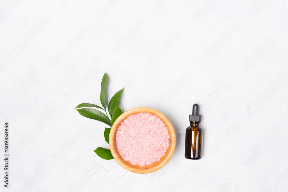 Beauty and spa concept. Sea salt, bottle of oil, green leaves on white background. Flat lay. Copy space. Beauty and spa concept. Sea salt, bottle of oil, green leaves on white background. Flat lay. Copy space.