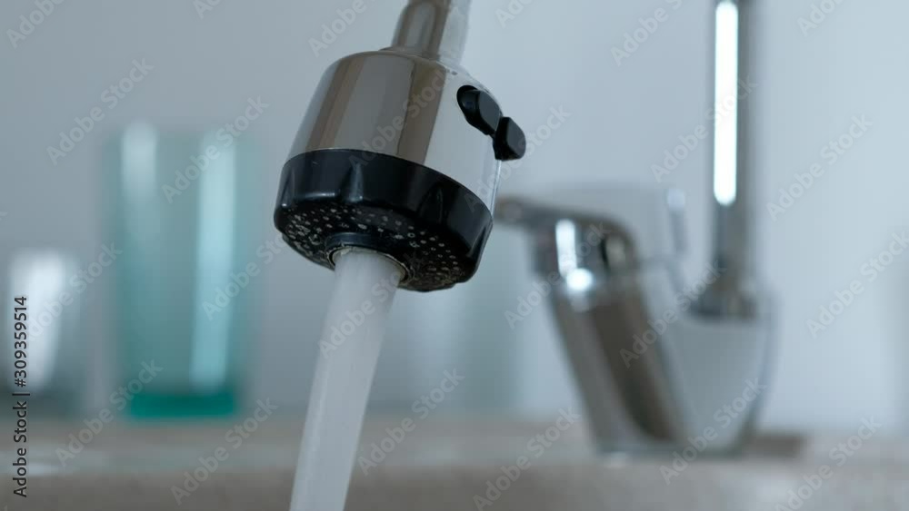 Close up - Tap water flows from tap in kitchen. Hands man in plaid shirt close tap in home on background clean glasses. Close up - Tap water flows from tap in kitchen. Hands man in plaid shirt close tap in home on background clean glasses.