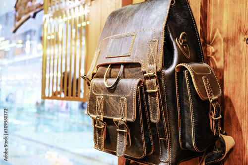 Leather backpacks and briefcases hang on the wall. The concept of stylish leather products. Bags, purses and belts.