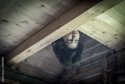 Upside down boy in wooden cottage