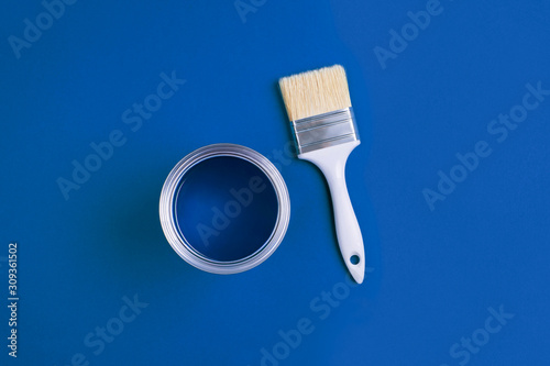 Fototapeta Naklejka Na Ścianę i Meble -  Paint brush with an open can of paint on trendy Classic Blue background. Color of the year 2020. Top view, flat lay.