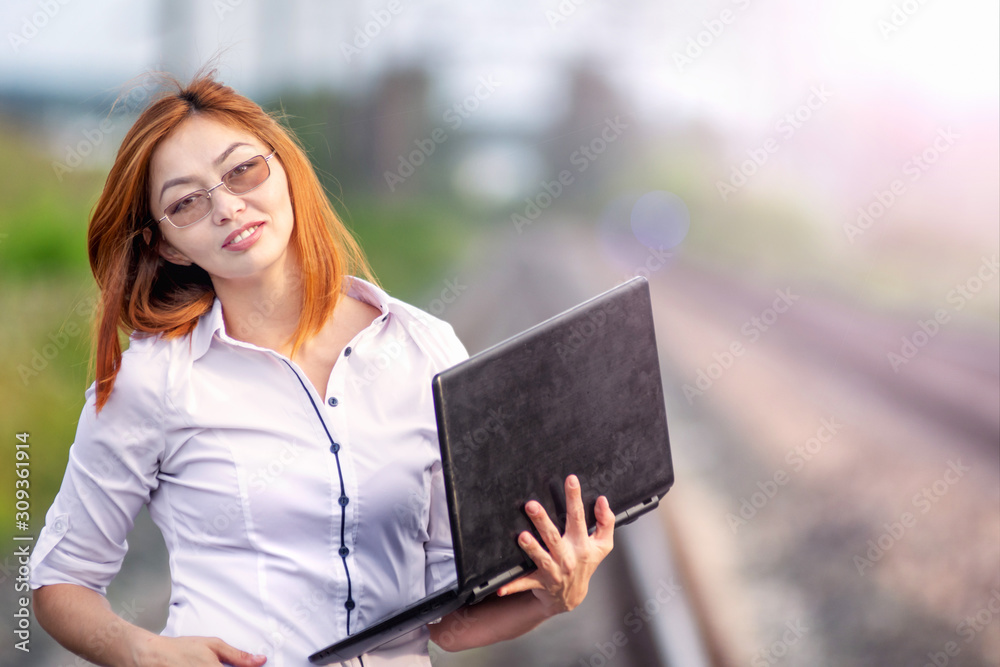 Portrait young and beautiful asian woman working with laptop while walking outdoor on the rails Portrait young and beautiful asian woman working with laptop while walking outdoor on the rails
