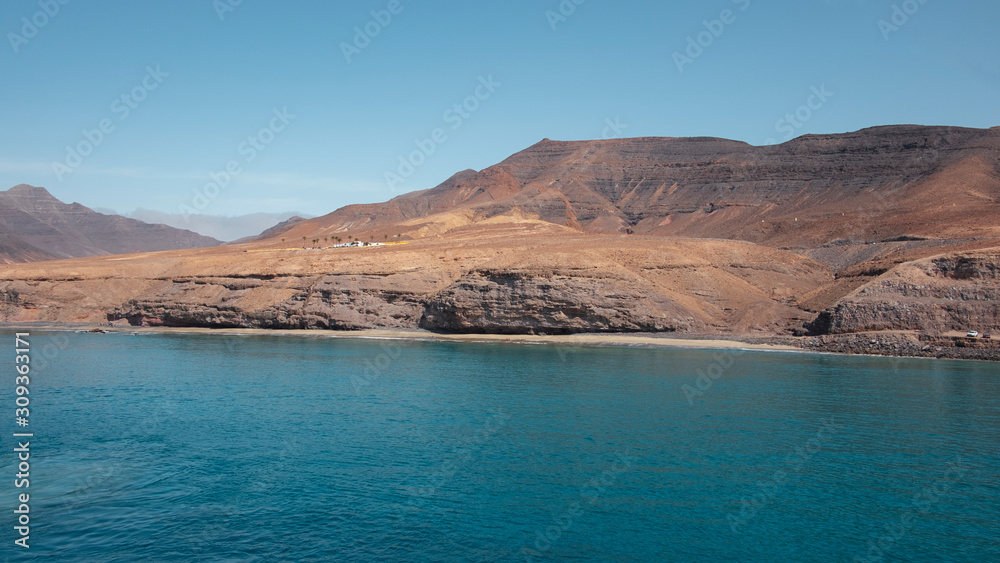 Approaching Fuerteventura island at its most southern point, at Morro Jable with the display of the solitary cliffs and arid mountains behind, part of the Parque Natural Jandia, Canary Islands, Spain